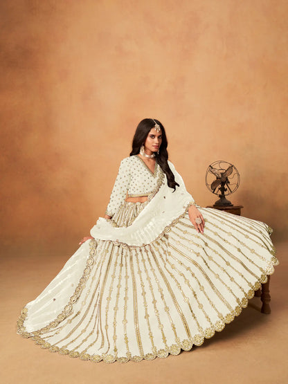 Model sitting wearing off white art silk lehenga choli with paper mirror and embroidery work