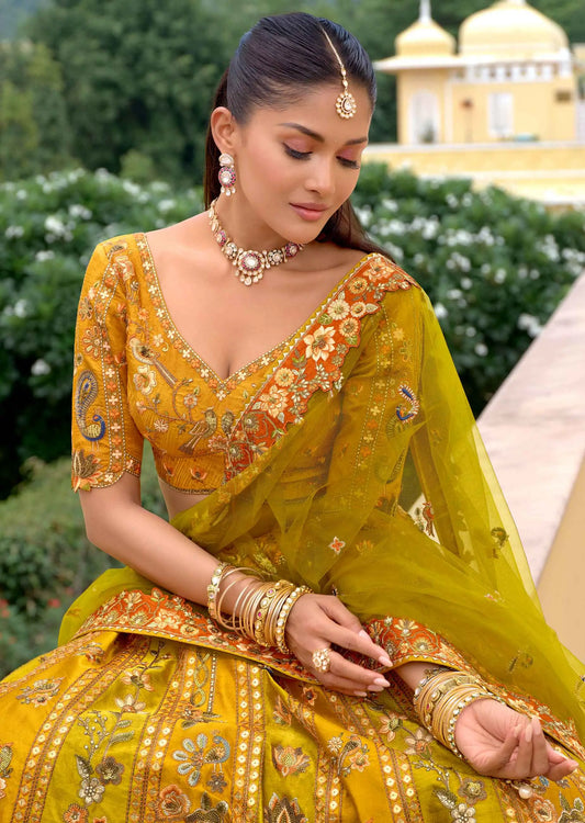 Model sitting wearing golden lehenga showing close-up of heavy embroidery and lotus work