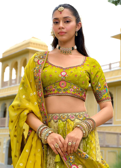 Model sitting wearing olive yellow lehenga with peacock embroidery work